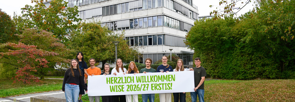 Titelbild Erstis Studierende stehen mit einem Herzlich Willkommen-Banner vor dem GB3.