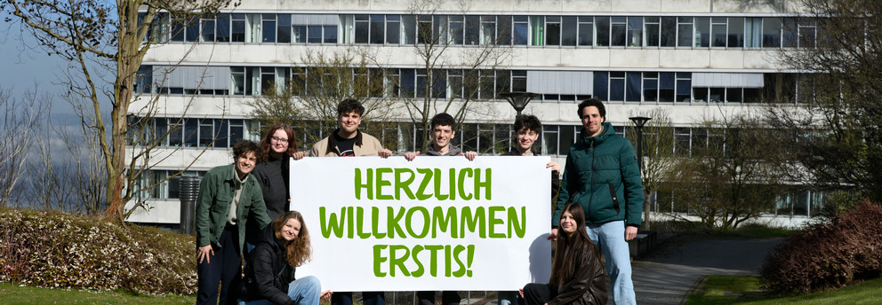 Titelbild Erstis Studierende stehen mit einem Herzlich Willkommen-Banner vor dem GB3.