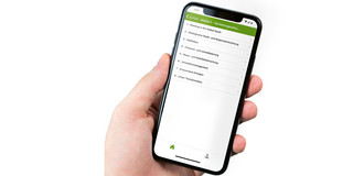 One hand holds a mobile phone with an open TU App to book courses.