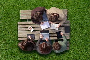 Studierende werden von der Vogelperspektive beim arbeiten draußen an einem Tisch gezeigt.