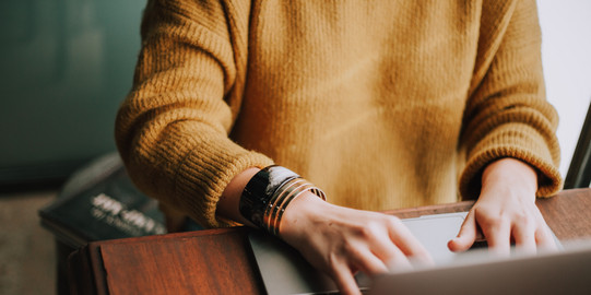 Arbeitsplatz Frau sitzt am Laptop und tippt etwas ein.