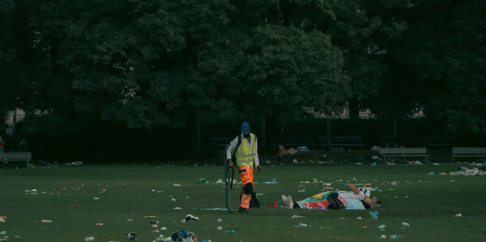 Müllentsorgung Mitarbeiter säubert Grünfläche.