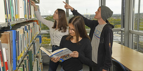 Studenten stehen vor Bücherregal.
