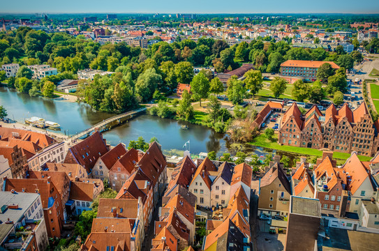 Lübeck (Modul 7) Lübeck aus der Vogelperspektive auf der man Wasser, Haussiedlungen und Wälder sehen kann.