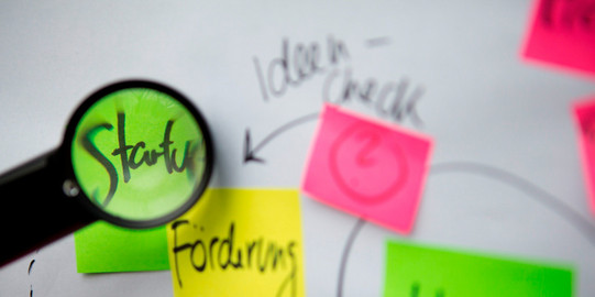 Pinnwand-Klebezettel Beschriftete bunte Klebezettel und eine Lupe, die die Schrift vergrößert.